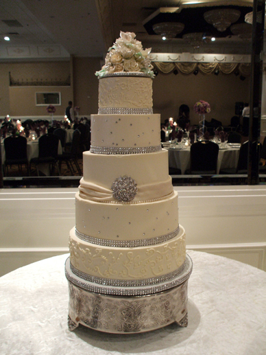 5 tier ivory wedding cake with diamond studs and buttercream scrolls and diamond ribbons for the borders