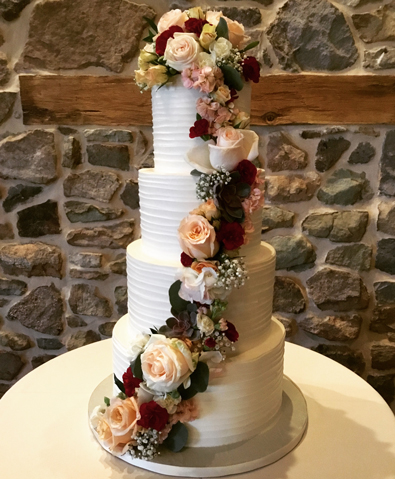 4 Tier rustic textured buttercream wedding cake decorated with cascading fresh flowers