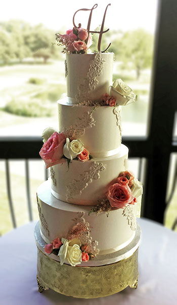 4 Tier buttercream wedding cake decorated with fondant lace and fresh flowers