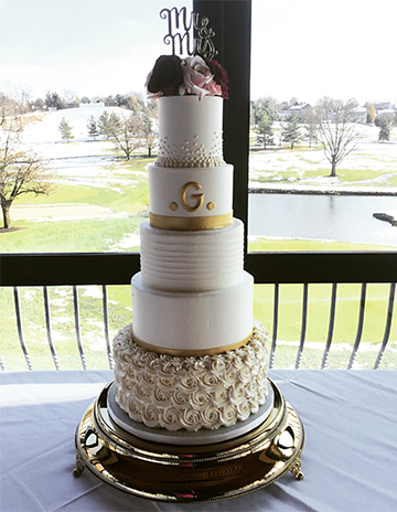 5 Tier buttercream wedding cake, decorated with buttercream bubbles, buttercream texture, gold fondant ribbons and initial, buttercream rosettes and fresh flowers delivered to Heritage Hills Golf Glub in East York PA