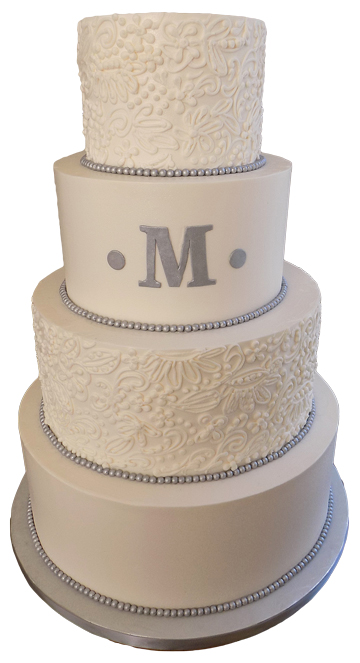 4 Tier buttercream wedding cake, decorated with buttercream lace designs, silver fondant pearl borders and a silver M monogram delivered at Wyndridge Farms Dallastown PA