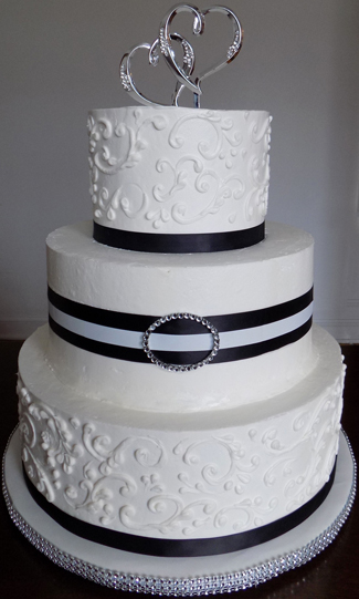 3 Tier buttercream wedding cake, decorated with scrolls, black ribbons and diamonds