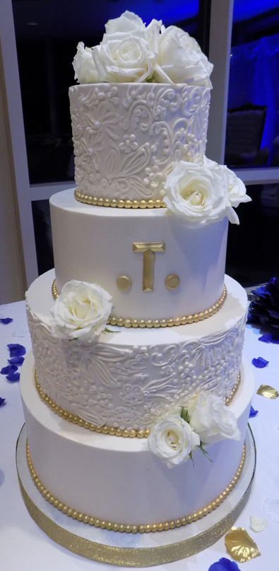 4 Tier buttercream wedding cake decorated with buttercream lace, edible gold borders and fresh roses.