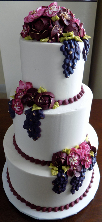 3 Tier buttercream wedding cake, decorated with an assortment of wine colored and burgundy buttercream flowers as well as grape clusted with gold hi-lights<br />
<em>Wedding Cakes York PA</em>